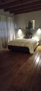 a bedroom with a bed and a wooden floor at Días y flores in Ranchos