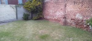 a corner of a brick wall with a grass yard at Días y flores in Ranchos
