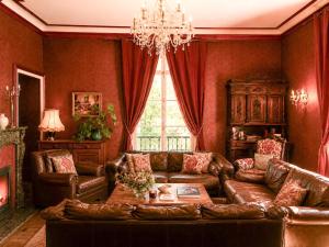 a living room with leather furniture and a chandelier at Private Château with sauna, hot tub & 4ha park - Château Guillermo in La Moncelle