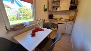 a small kitchen with a white table with flowers on it at Ferienwohnung Strandweg 1 in Wieck