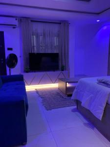 a bedroom with purple lighting and a bed and a tv at PrimeNest Apartment in Lekki