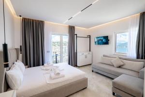 a white bedroom with a bed and a couch at Mariana Apartments in Sarandë