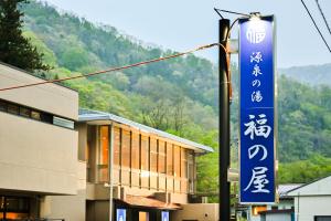 ein Schild an einer Straßenlaterne neben einem Gebäude in der Unterkunft 源泉の湯 福の屋 in Minakami