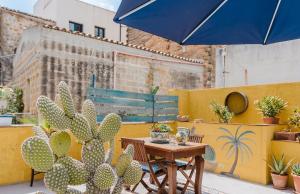 a table and chairs with a blue umbrella and cactus at Casa d'Artista con Terrazza Panoramica nel Borgo" Ajman house in Sambuca di Sicilia