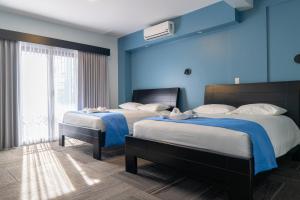 two beds in a room with blue walls at Hotel Luckys in San Isidro de El General +4 photos
