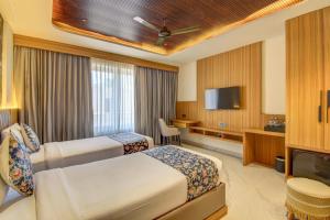 a hotel room with two beds and a flat screen tv at The White Castle Hotel in Mysore +26 photos