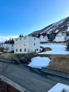 a white building with snow in front of a mountain at Chic Townhouse - Views Telescope Balcony BBQ in Siglufjörður