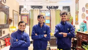 three men standing in a room with their arms crossed at On the House homestay in New Delhi