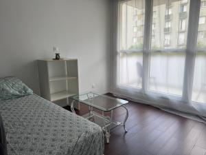 ein Schlafzimmer mit einem Bett und einem Tisch neben einem Fenster in der Unterkunft Yara in Montargis