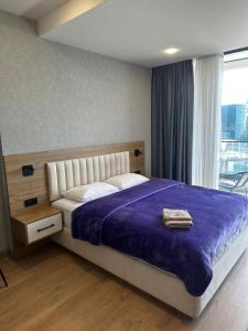a bedroom with a large bed with a purple blanket at Paradise Apartments Solis in Batumi