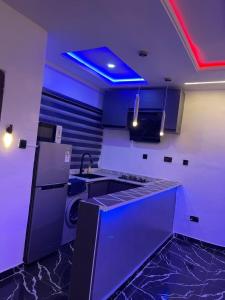 a kitchen with purple lighting and a sink and a refrigerator at PrimeNest Apartment in Lekki +6 photos