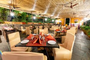 a dining room with tables and white chairs at Fort JadhavGADH -A GADH Heritage Hotel in Pune