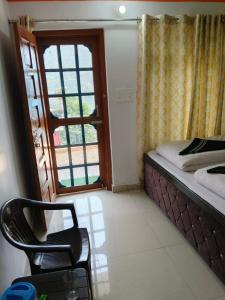 a bedroom with a bed and a window and a chair at Vinod Tourist Lodge in Gupta Kāshi +5 photos