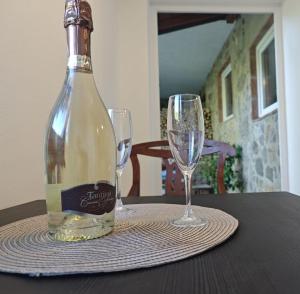 a bottle of wine sitting on a table with two glasses at Sobe - Rooms NININ in Deskle