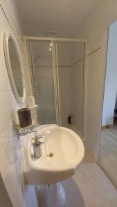 a white bathroom with a sink and a mirror at Chambre d'hôtes Saumur-Champigny 2 personnes in Montreuil-Bellay