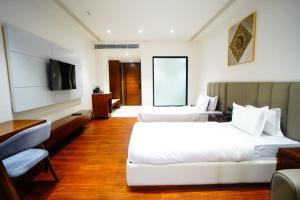 a hotel room with two beds and a flat screen tv at Veerasa Hotel in Hanumāngarh