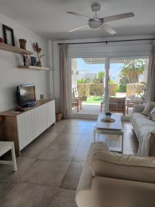 a living room with a couch and a tv at Casa adosada Rompeolas-Atlanterra in Zahara de los Atunes