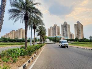 a white van driving down a road with tall buildings at Shastik Residency in Oragadam