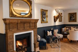 a living room with a fireplace and a mirror at Dunalastair Hotel Suites in Kinloch Rannoch