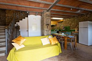 a living room with a yellow couch and a kitchen at L'Antic ajuntament de la Torra in La Baronia de Rialb