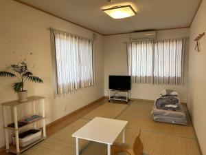 a living room with a table and a tv at 小さなペンション Branchee in Kushimoto