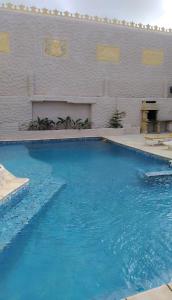 a swimming pool with blue water in front of a white wall at Villa avec piscine in Korba