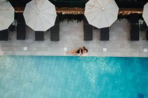 a woman swimming in a swimming pool with umbrellas at Petit Sagitario Adults only in Ciutadella