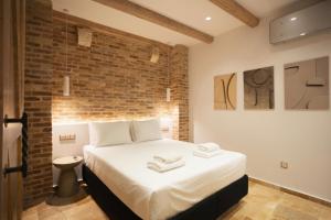 a bedroom with a large white bed with a brick wall at Arco Segreto Apartment, Old Town in Corfu