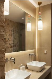 a bathroom with a sink and a mirror and two lights at Arco Segreto Apartment, Old Town in Corfu