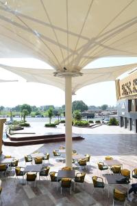 a patio with tables and chairs under a white umbrella at Pride Elite Himmatnagar in Sonāsan