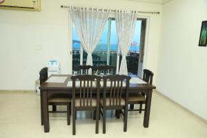 a dining room table with chairs and a large window at Shastik Residency in Oragadam +22 photos