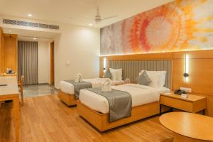 a hotel room with two beds and a table at Pride Elite Himmatnagar in Sonāsan +45 photos