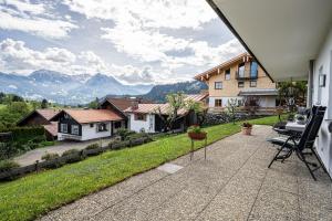 a patio with a view of a house and mountains at Ferienwohnung Kircher in Obermaiselstein