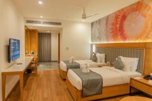 a bedroom with two beds and a desk and a television at Pride Elite Himmatnagar in Sonāsan