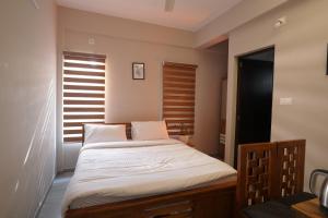 a bedroom with a bed with white sheets and a window at Blue Pearl Residency in Trivandrum