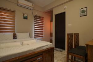 a bedroom with a bed and a chair and a window at Blue Pearl Residency in Trivandrum