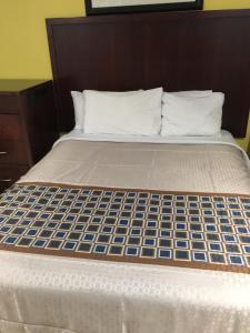 a bed with a brown headboard and blue and white mattress at Crenshaw Inn Motel in Los Angeles
