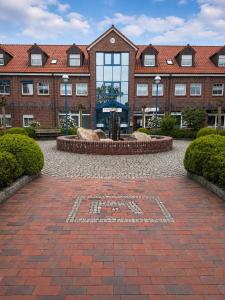 a large brick building with a sign on a brick courtyard at Sporthotel Middelpunkt in Aurich