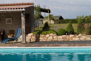 a swimming pool with a blue chair next to a house at La Maison Bornat in Versaugues