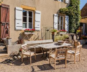 a wooden table and chairs in front of a building at La Maison Bornat in Versaugues