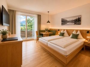 a hotel room with a bed and a desk and a window at MÜHLBACHER - inklusive kostenfreiem Eintritt in die Alpentherme in Bad Hofgastein