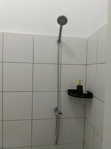 a shower in a white tiled bathroom at Ina Guesthouse in Lovina