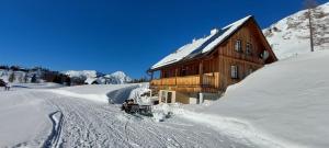a man riding a snowboard in the snow near a house at Gindlhütte in Tauplitzalm