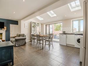 a kitchen and living room with a table and chairs at Greenrush Cottage in Blakeney