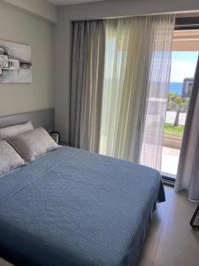 a bedroom with a blue bed and a large window at Villa Olivia Skioni in Nea Skioni
