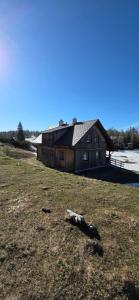 a barn in a field next to a body of water at Gindlhütte in Tauplitzalm +5 photos