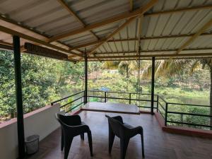 a room with two chairs and a table on a balcony at Adan Paradise Riverview Homestay in Attappādi