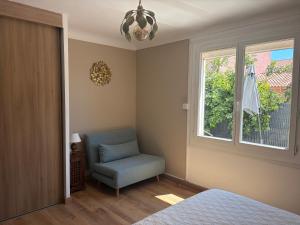 a bedroom with a blue chair and a window at Maison 5mn de la mer in Fréjus