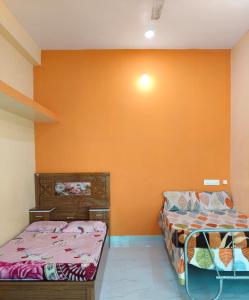 two beds in a room with an orange wall at Swami's Yatri nivas in Akalkot