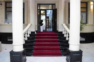 a staircase in a building with a red carpet and columns at Veranda XF Hotel in Samarkand